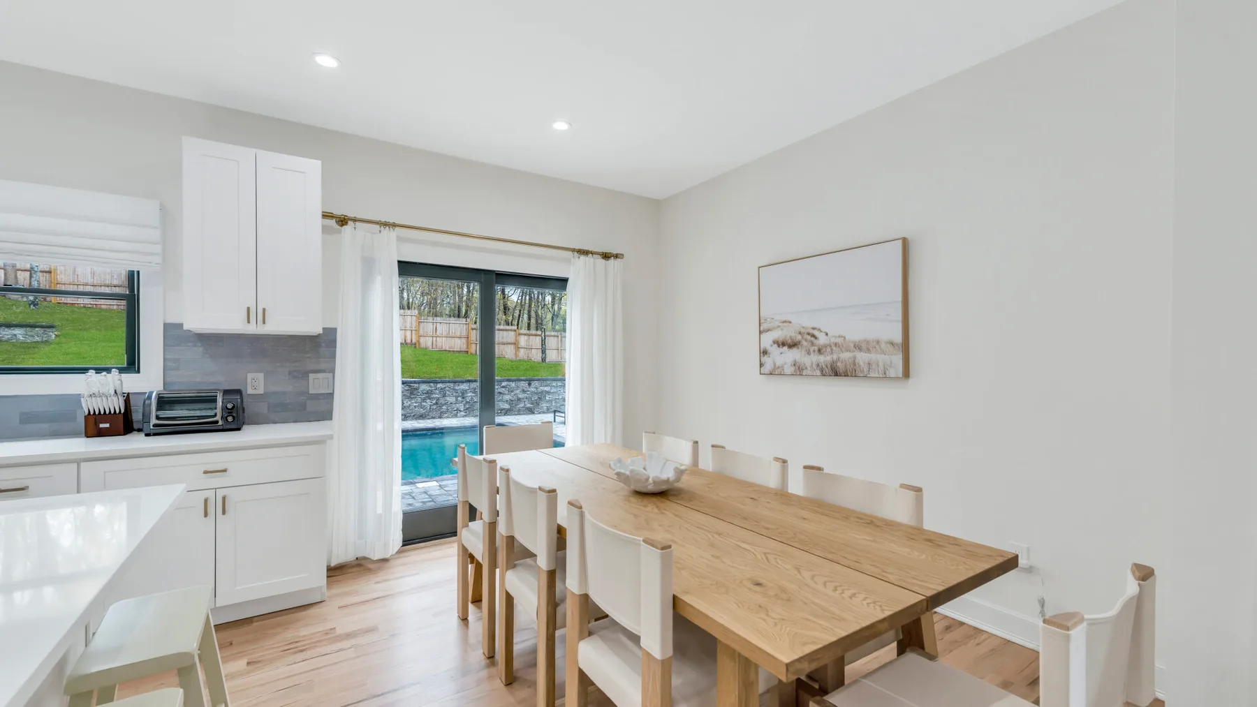 Un comedor luminoso con una mesa larga de madera junto a la cocina y puertas corredizas de vidrio.