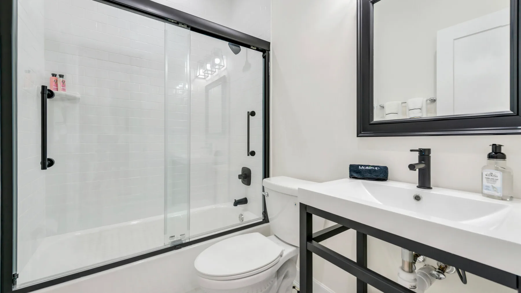 Un baño con ducha de vidrio, inodoro y lavabo.
