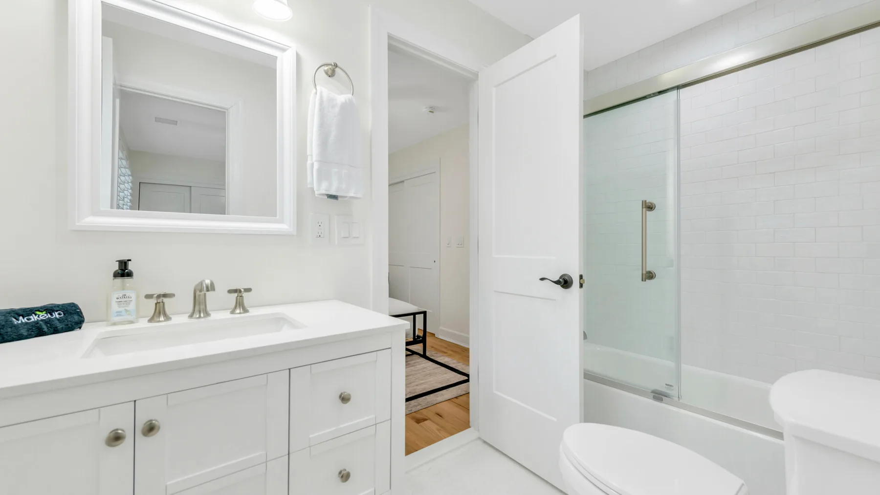 Un baño luminoso con lavabo, espejo y ducha de vidrio.