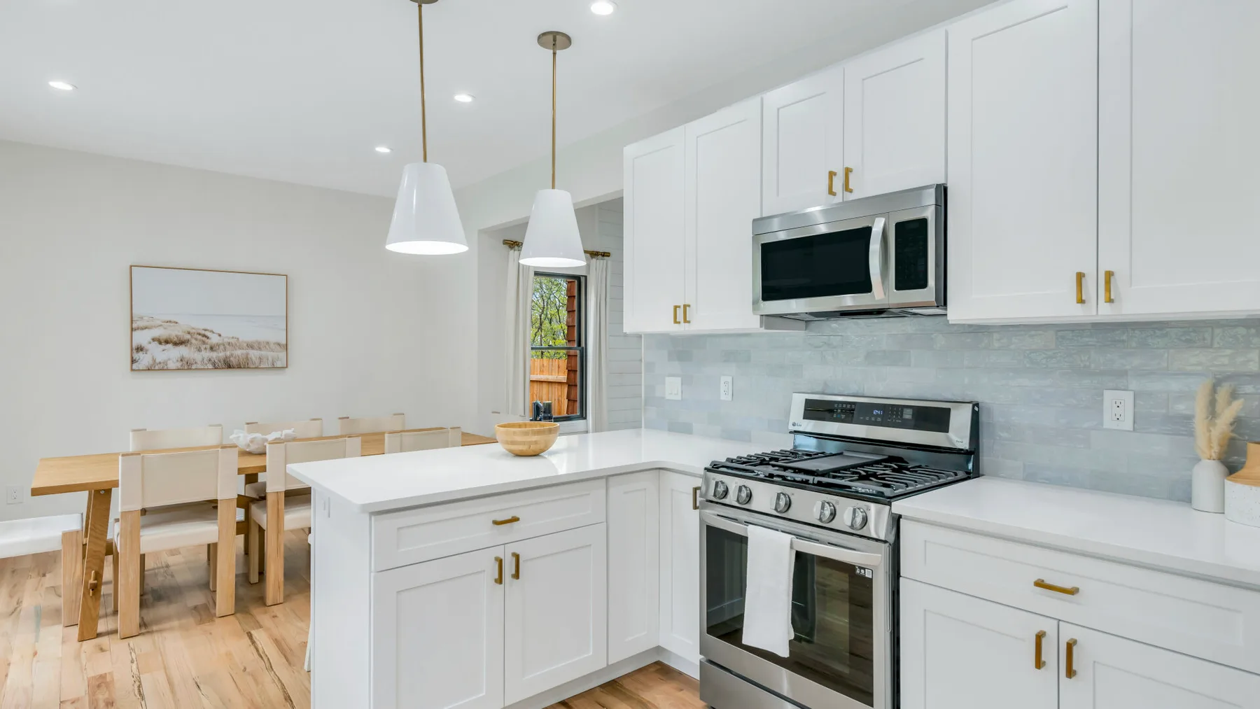Una cocina luminosa con gabinetes blancos, una estufa y una mesa de comedor.