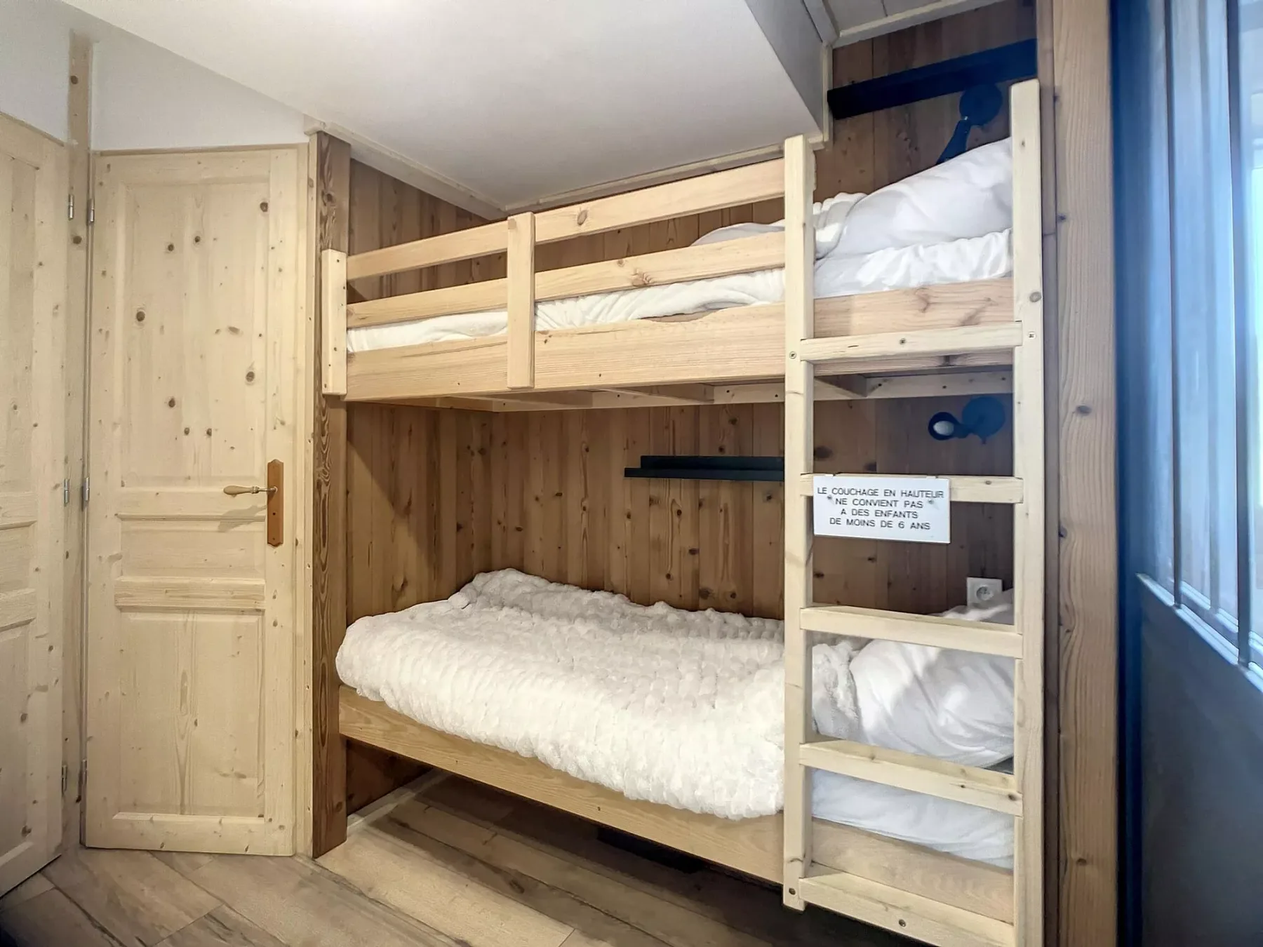 Un dormitorio con literas, paredes de madera y una ventana junto a las camas.