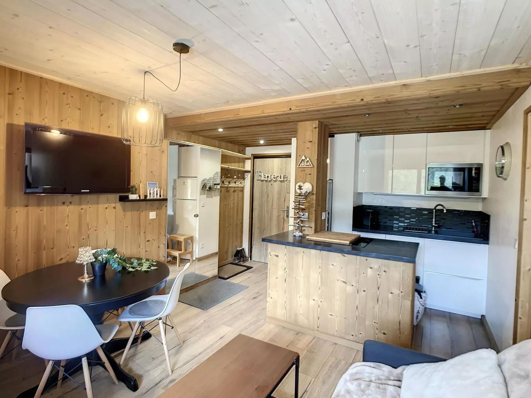 Una sala de estar y cocina de planta abierta, revestida de madera, con mesa de comedor y barra.