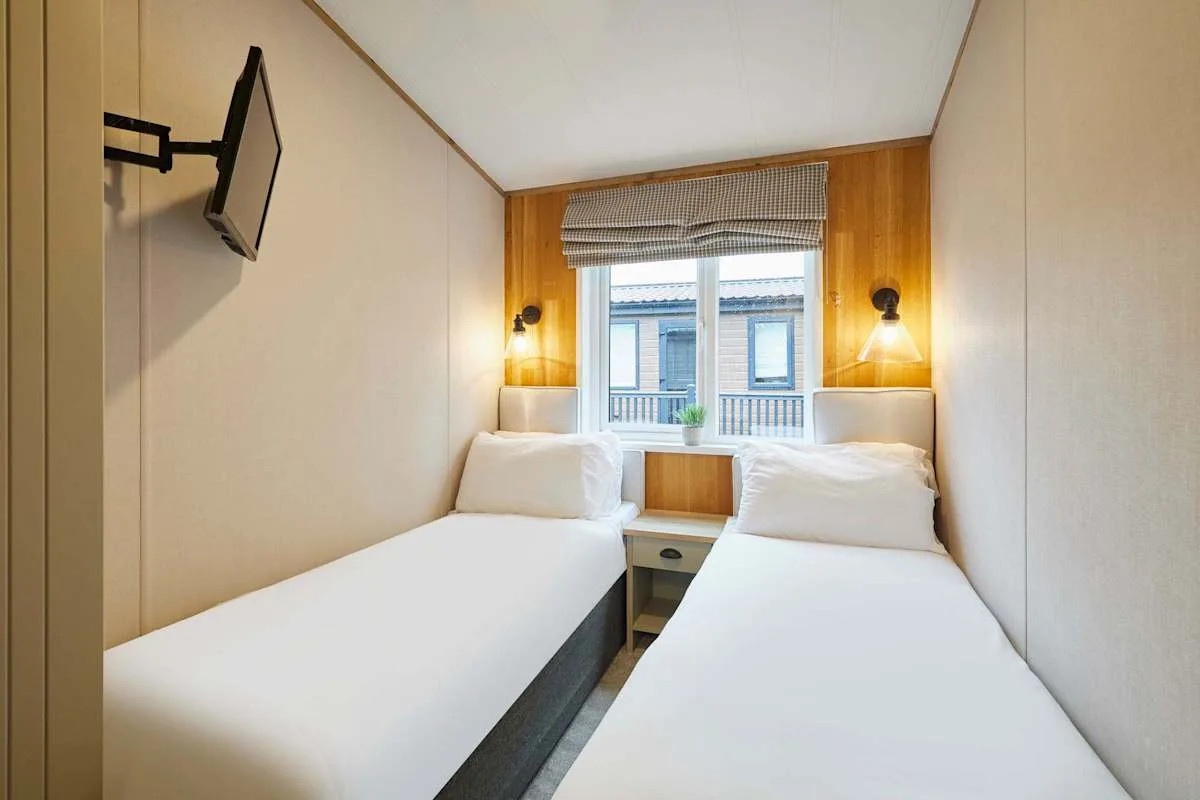 Un dormitorio compacto con dos camas individuales y una ventana entre ellas.