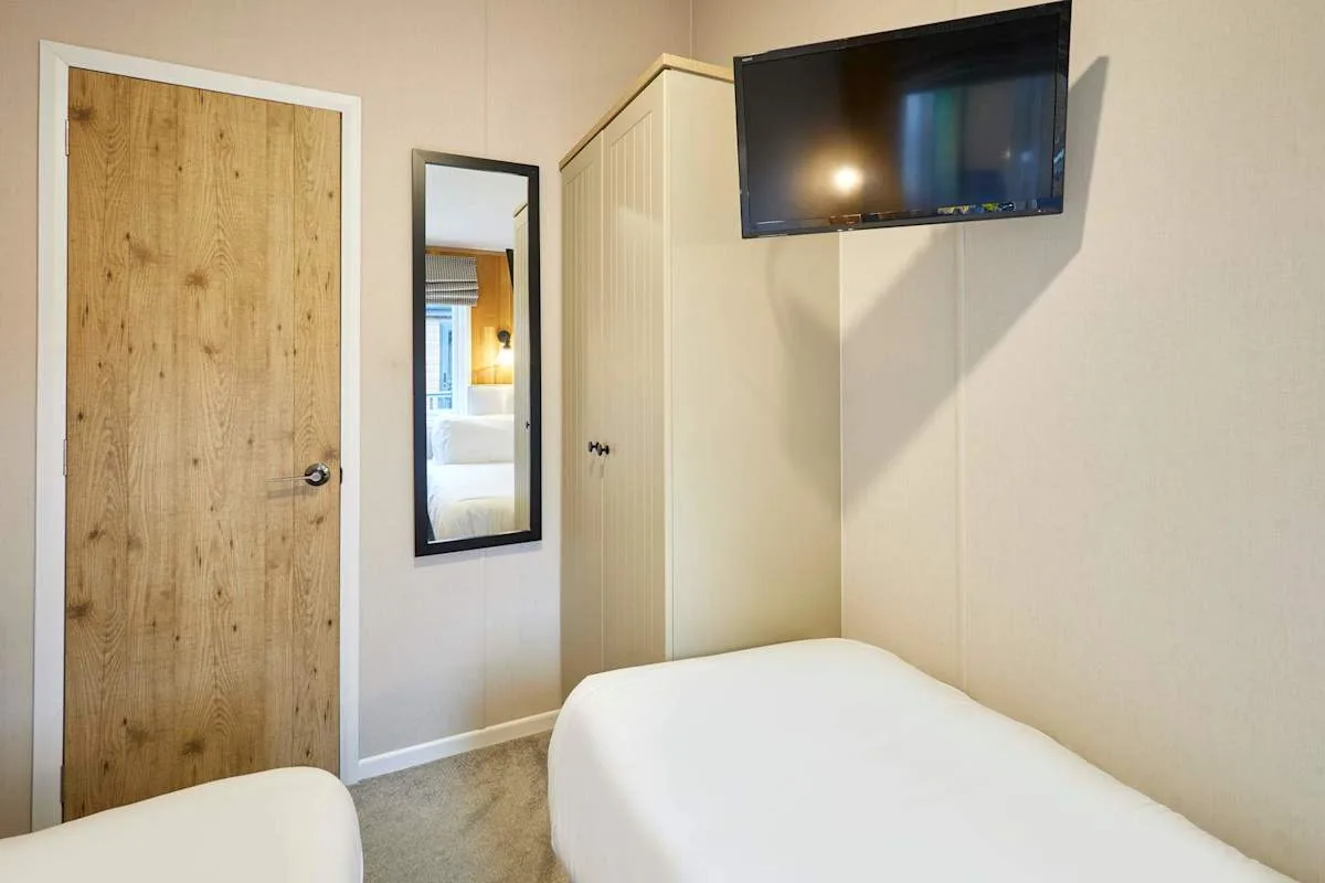 Un dormitorio con una cama, una puerta de madera y un televisor en la pared.