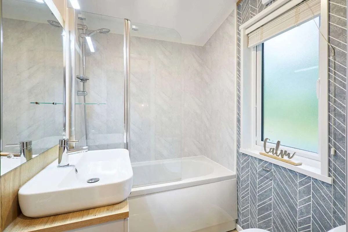 Un baño luminoso con lavabo, bañera y ventana esmerilada.