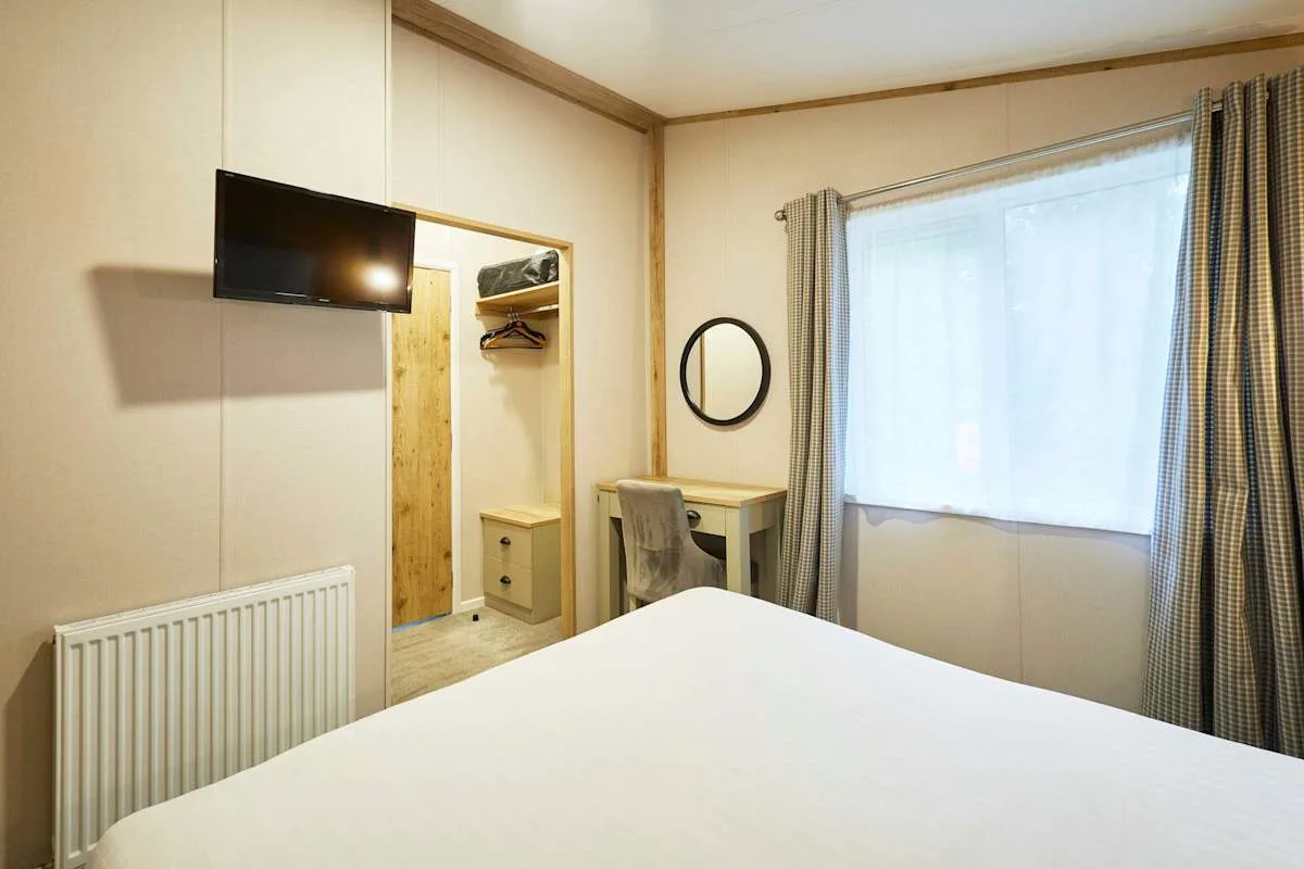 Un dormitorio con cama, escritorio y una gran ventana con cortinas.