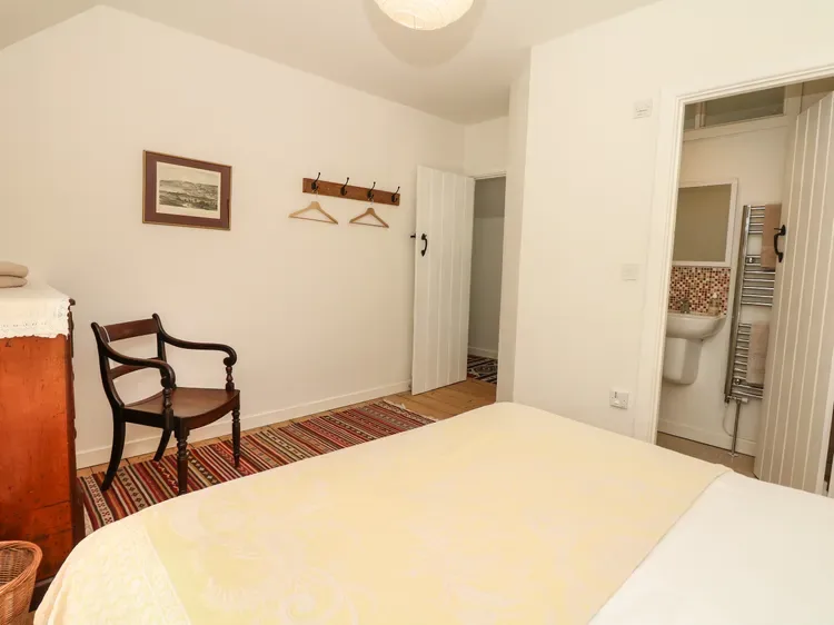 Un dormitorio con una cama, una silla y una puerta abierta al baño.