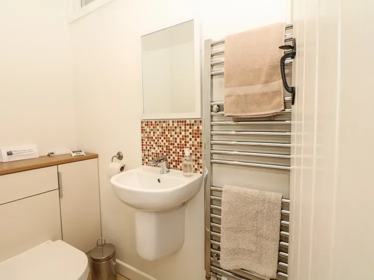 Un baño con lavabo de pared y un toallero calefactable.
