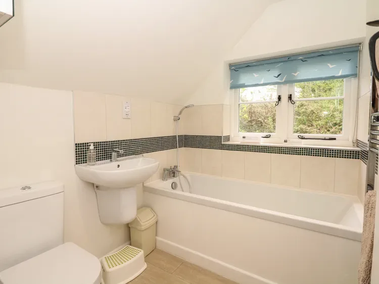 Un baño con bañera, lavabo y ventana.