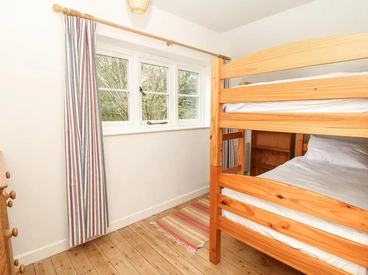 Un dormitorio con una litera de madera, una ventana y cortinas a rayas.