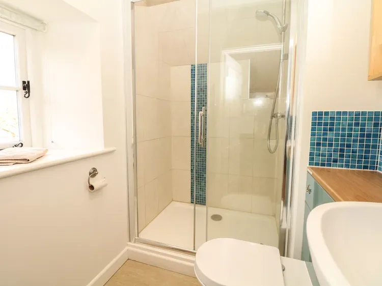 Un baño luminoso con ducha de vidrio y detalles de azulejos azules.