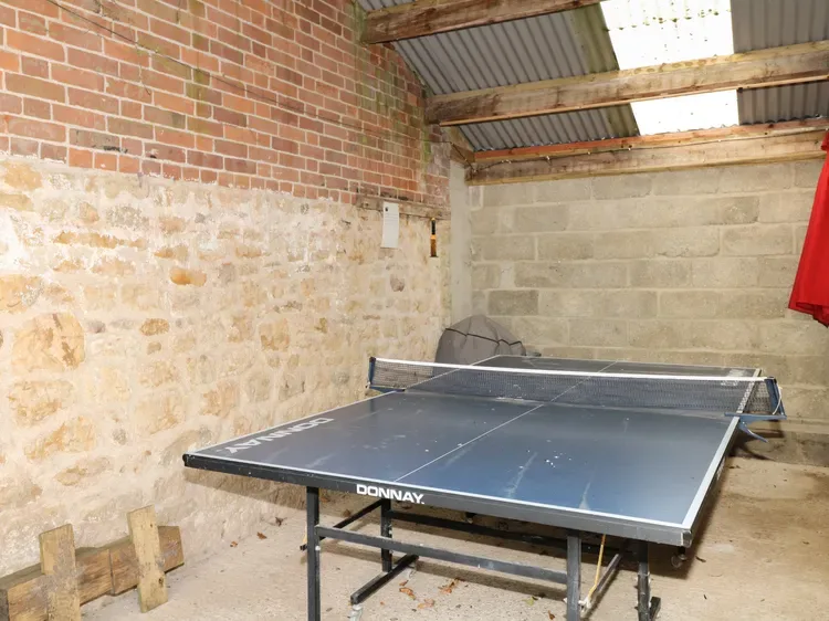 Una mesa de tenis de mesa está en una sala cubierta de ladrillo y piedra.