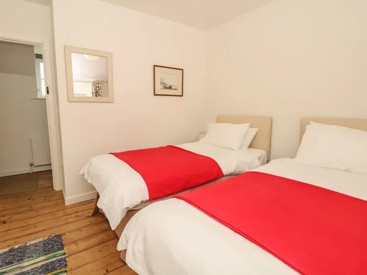 Un dormitorio con dos camas, ropa de cama blanca y cubrecamas rojos.