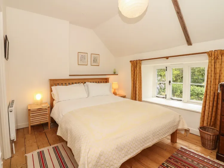 Un dormitorio luminoso con una cama grande, mesitas de noche y una ventana con cortinas.