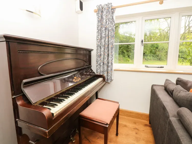 Una sala de estar con un piano vertical junto a una ventana.