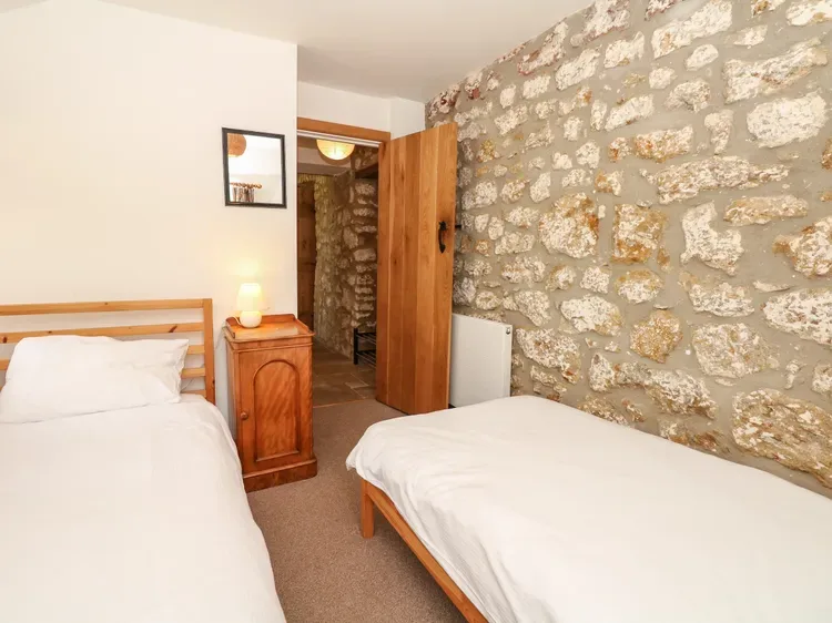 Un dormitorio con dos camas y una pared de piedra.