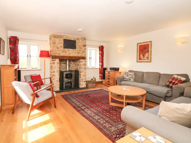 A living room with a stone fireplace, sofas, and a patterned rug.