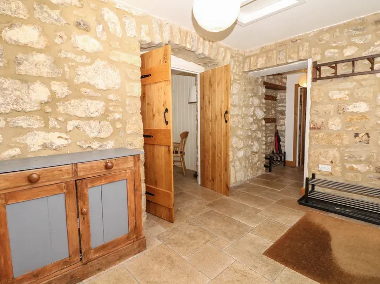 A stone-walled interior with an open wooden doorway and a tiled floor.