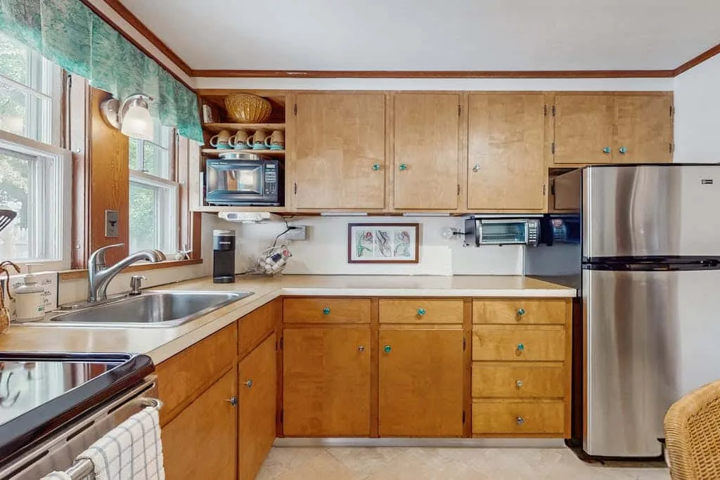A kitchen with wooden cabinets, a sink, and a refrigerator.