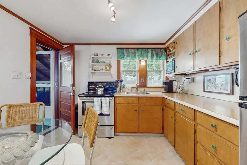 A kitchen with wooden cabinets, a stove, and a glass-topped dining table.