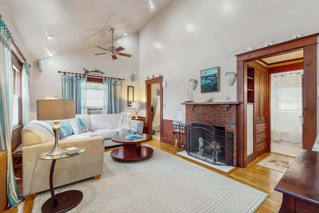 Living room with seating arranged around a coffee table beside a brick fireplace.