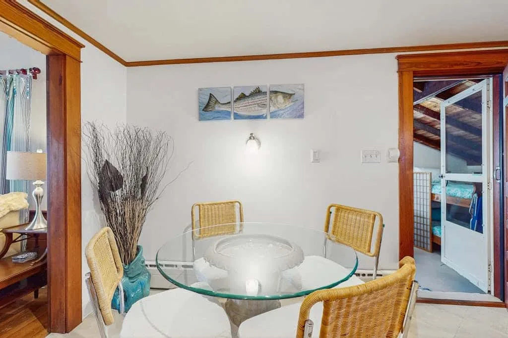 A dining area with a round glass table and woven seating.