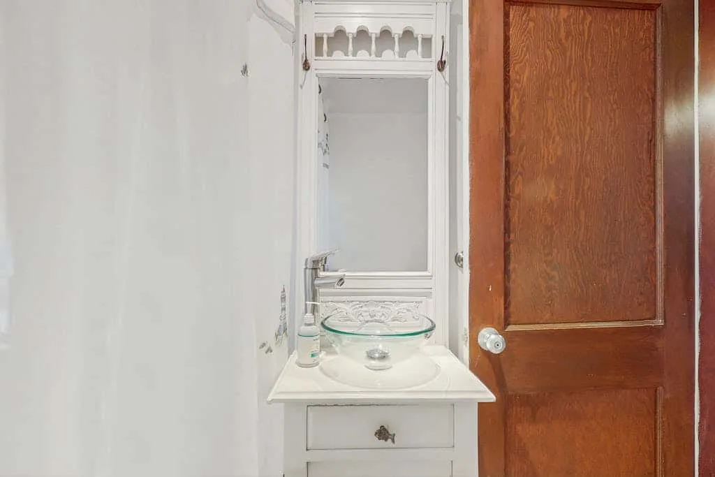 A bathroom vanity with a sink stands beside an open wooden door.