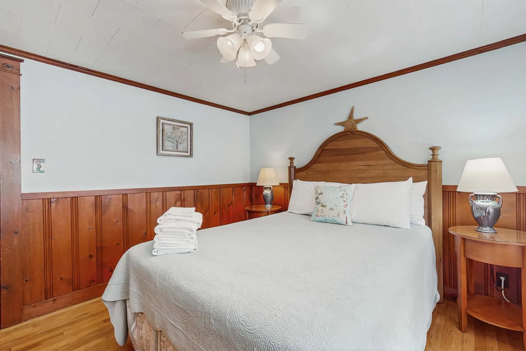 A bedroom with a neatly made bed, wooden headboard, and bedside lamps.