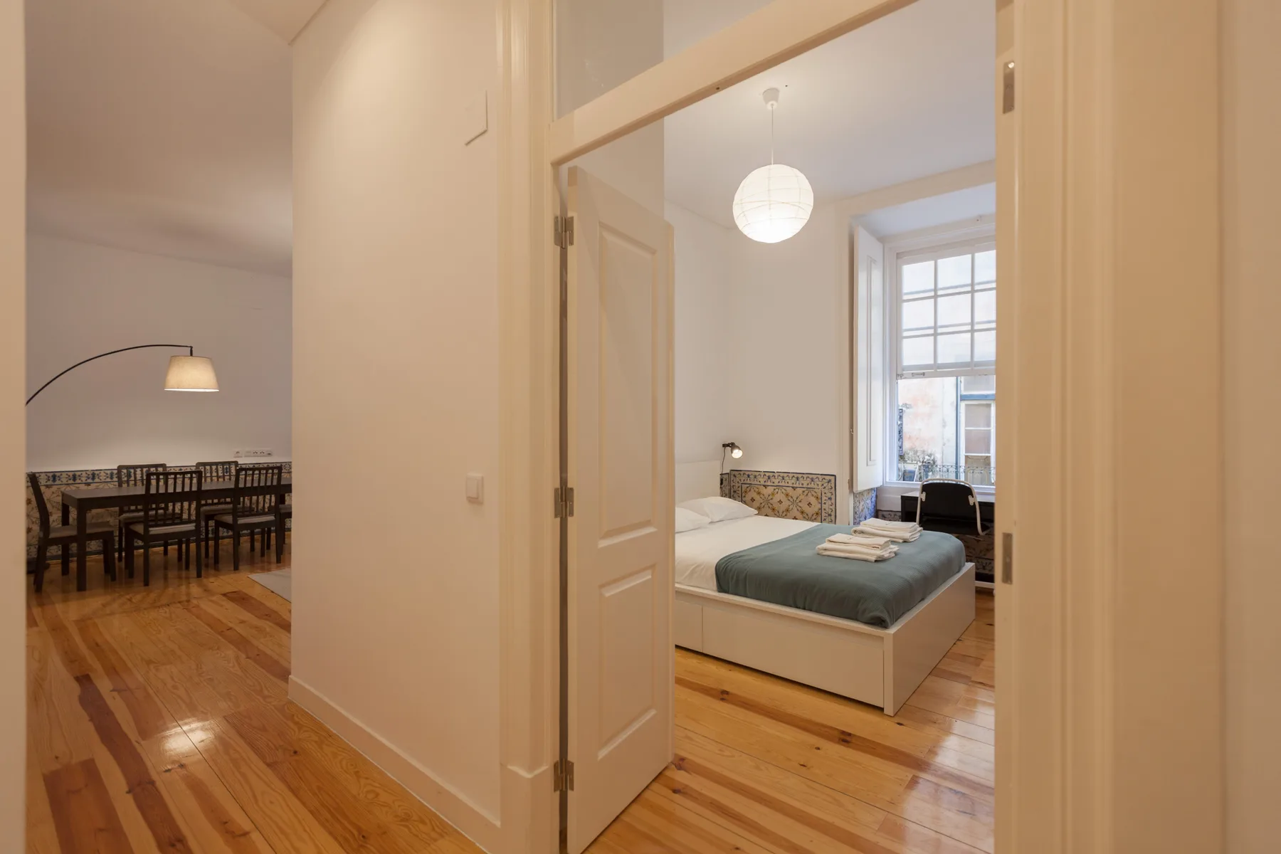 Dormitorio con una cama y una zona de comedor visible a través de la puerta.
