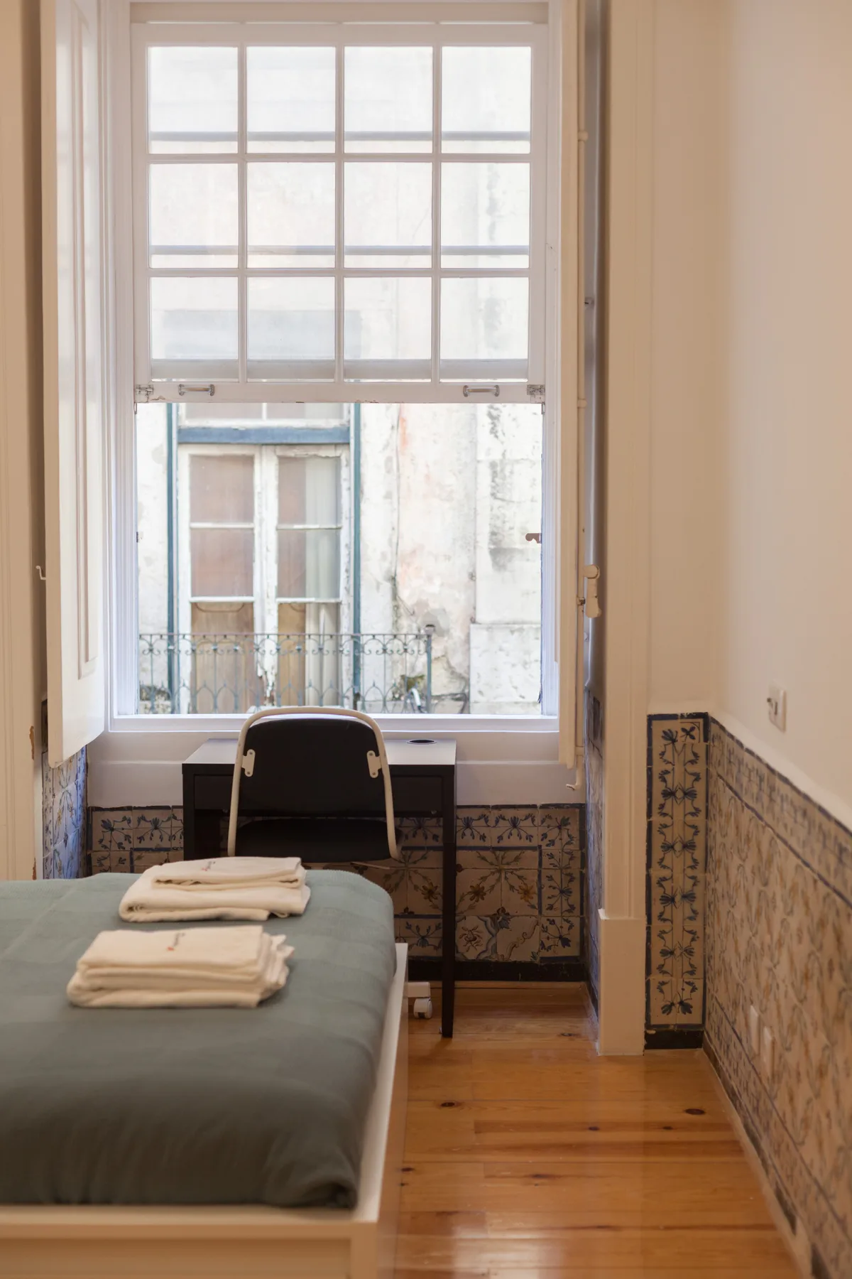 Un dormitorio con una cama, toallas dobladas y una ventana grande.