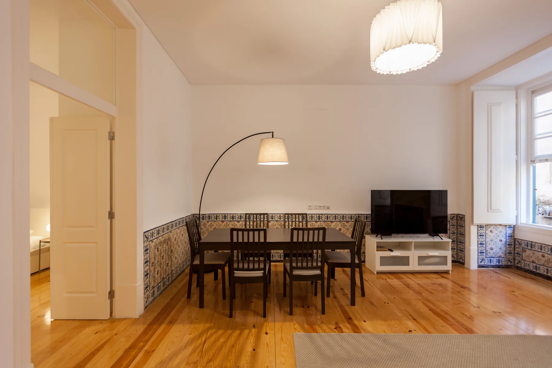Comedor con una mesa de madera y sillas junto a un televisor.