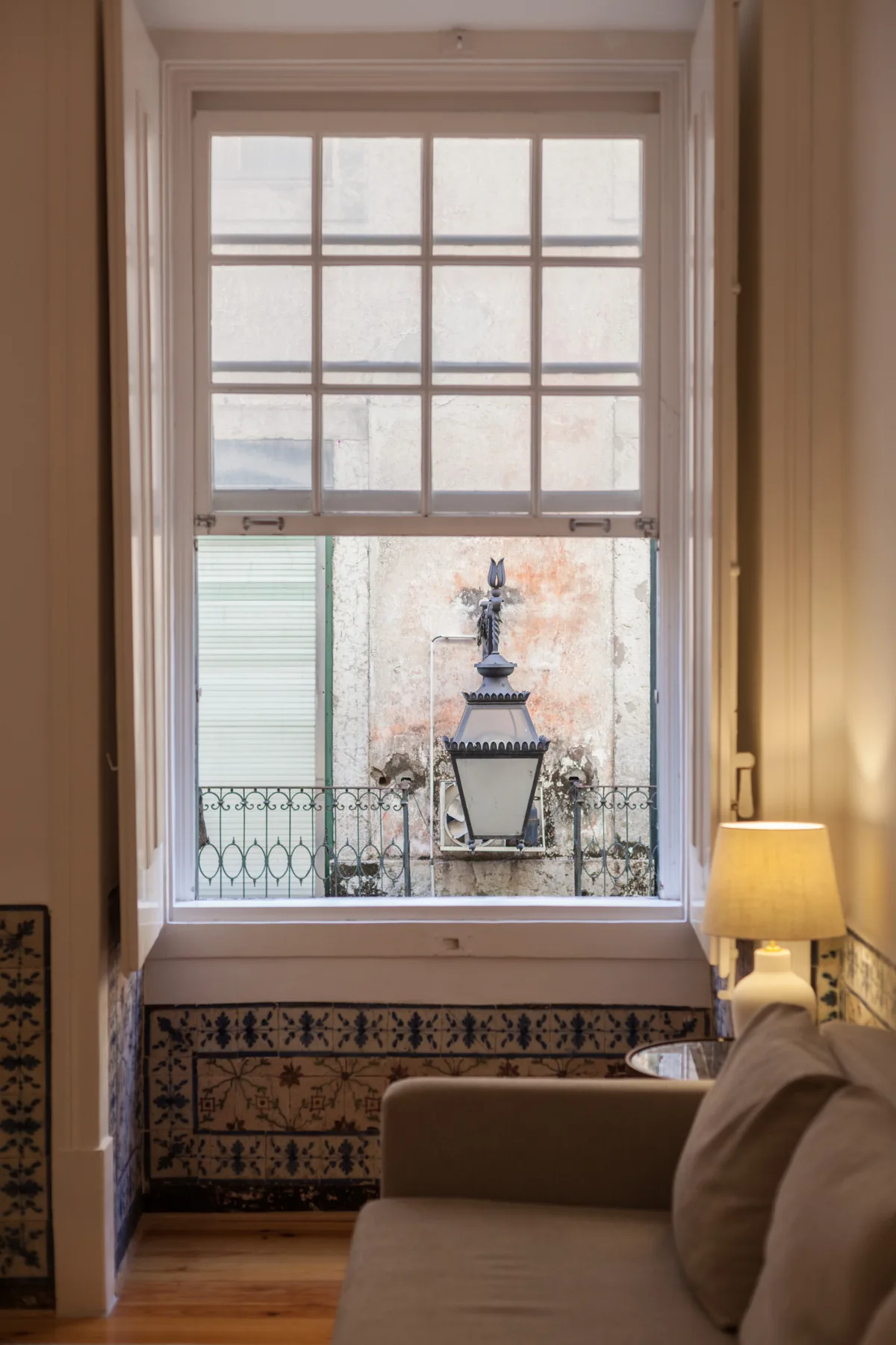 Una sala de estar con una ventana alta que da a una pared exterior con azulejos.