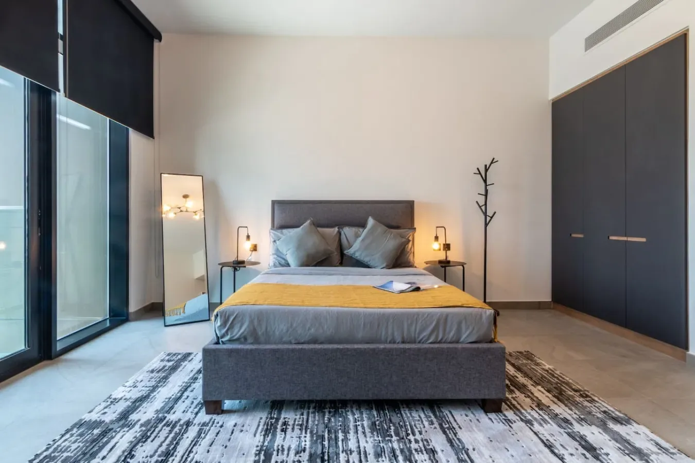 Un dormitorio moderno con una cama centrada y armarios oscuros grandes.