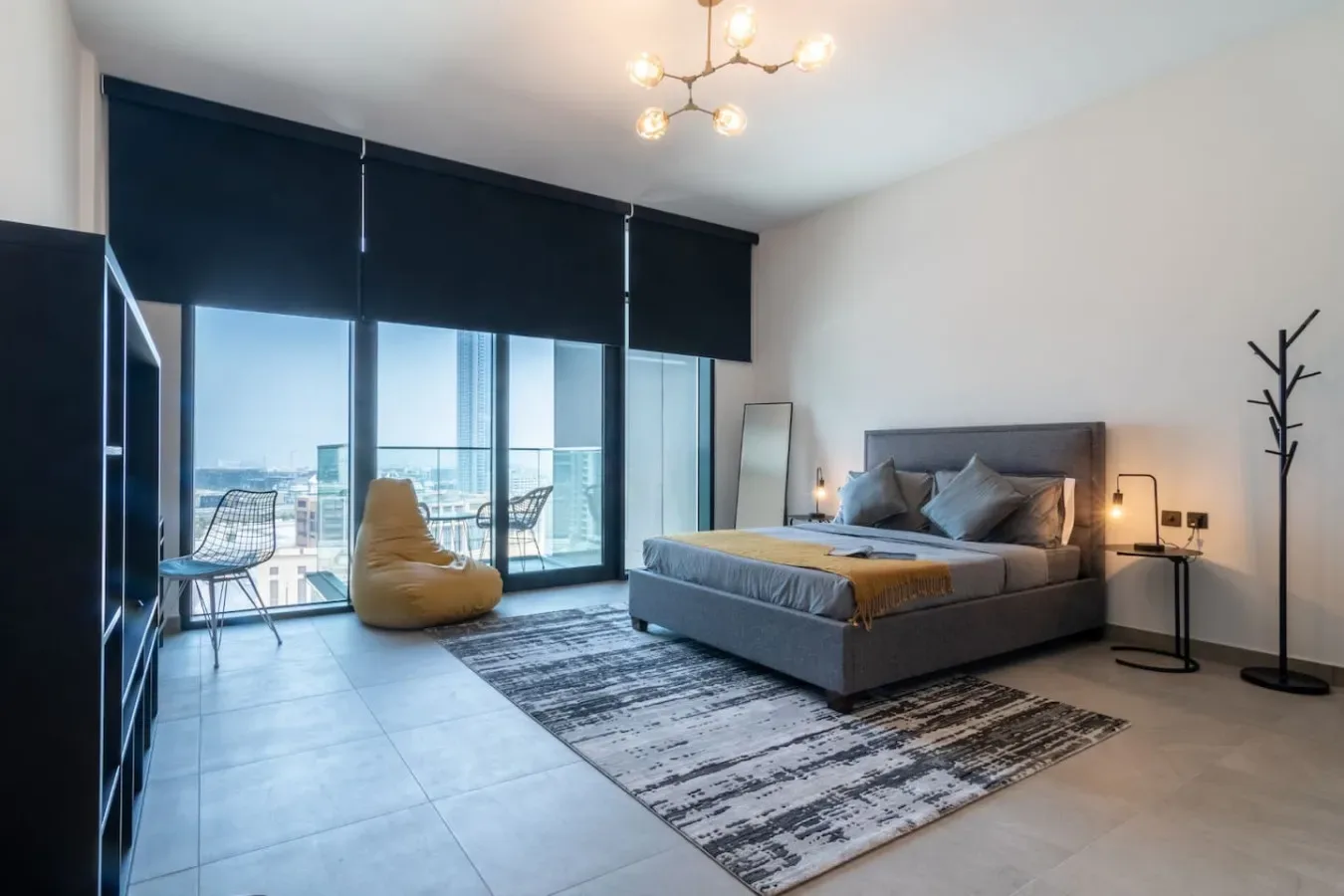 Un dormitorio moderno con una cama junto a ventanales y un balcón.
