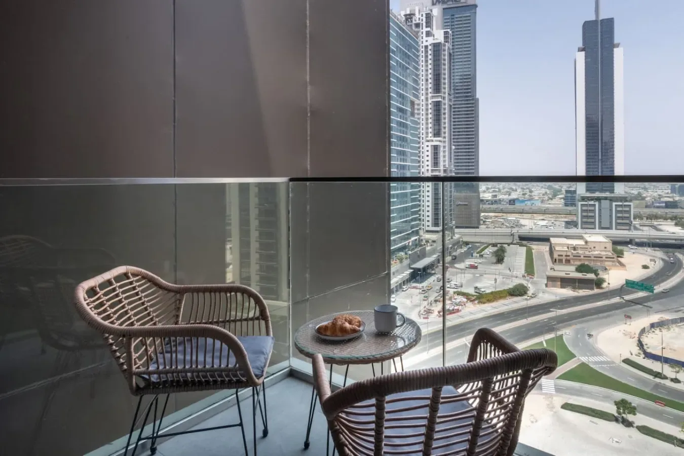 Una zona de estar en el balcón da a edificios y vías de la ciudad.