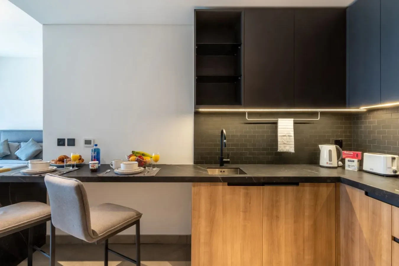 Una cocina moderna con gabinetes oscuros, una encimera y un comedor.