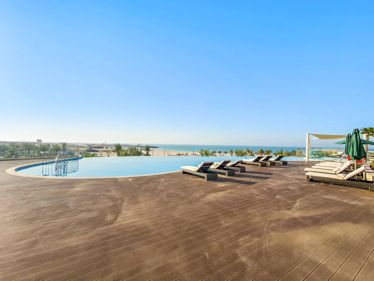 Una terraza con piscina y asientos reclinables tiene vistas al mar.