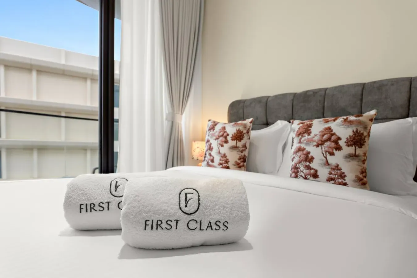 Dormitorio con una cama bien tendida y cojines decorativos estampados.