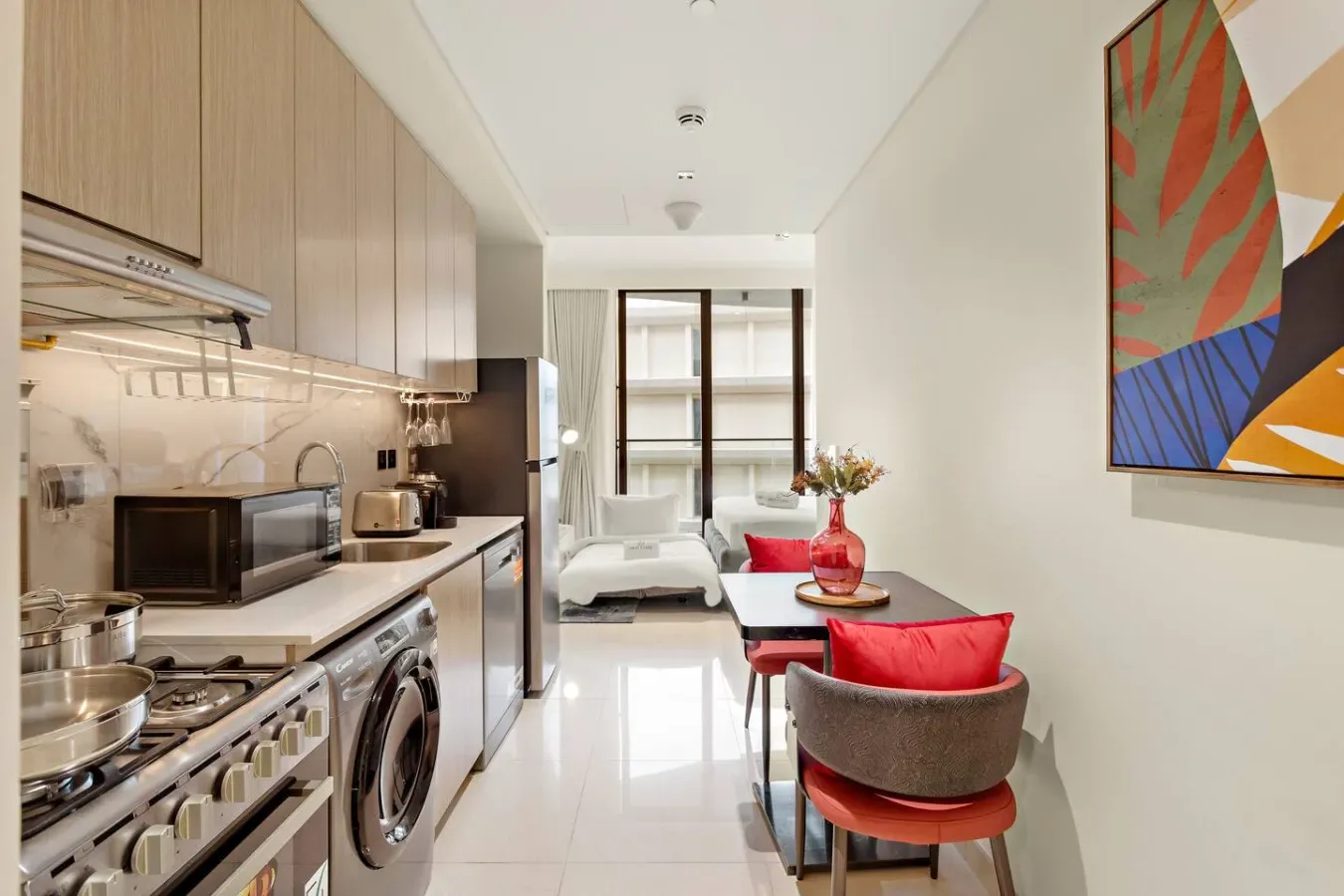 Una cocina compacta y un comedor se abren a una luminosa sala de estar junto a una ventana grande.