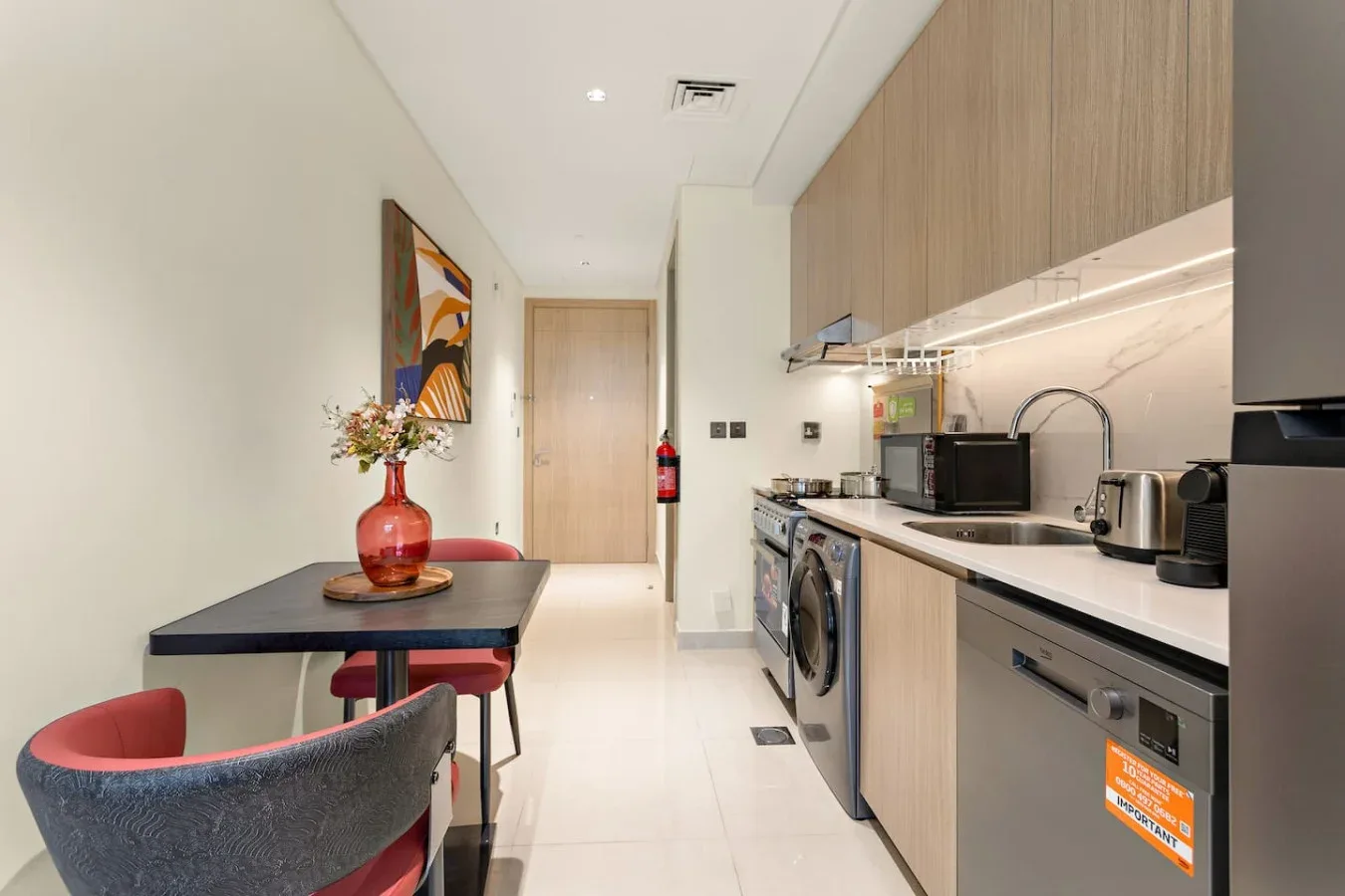 Una cocina compacta con zona de comedor, mesa, asientos y electrodomésticos integrados.