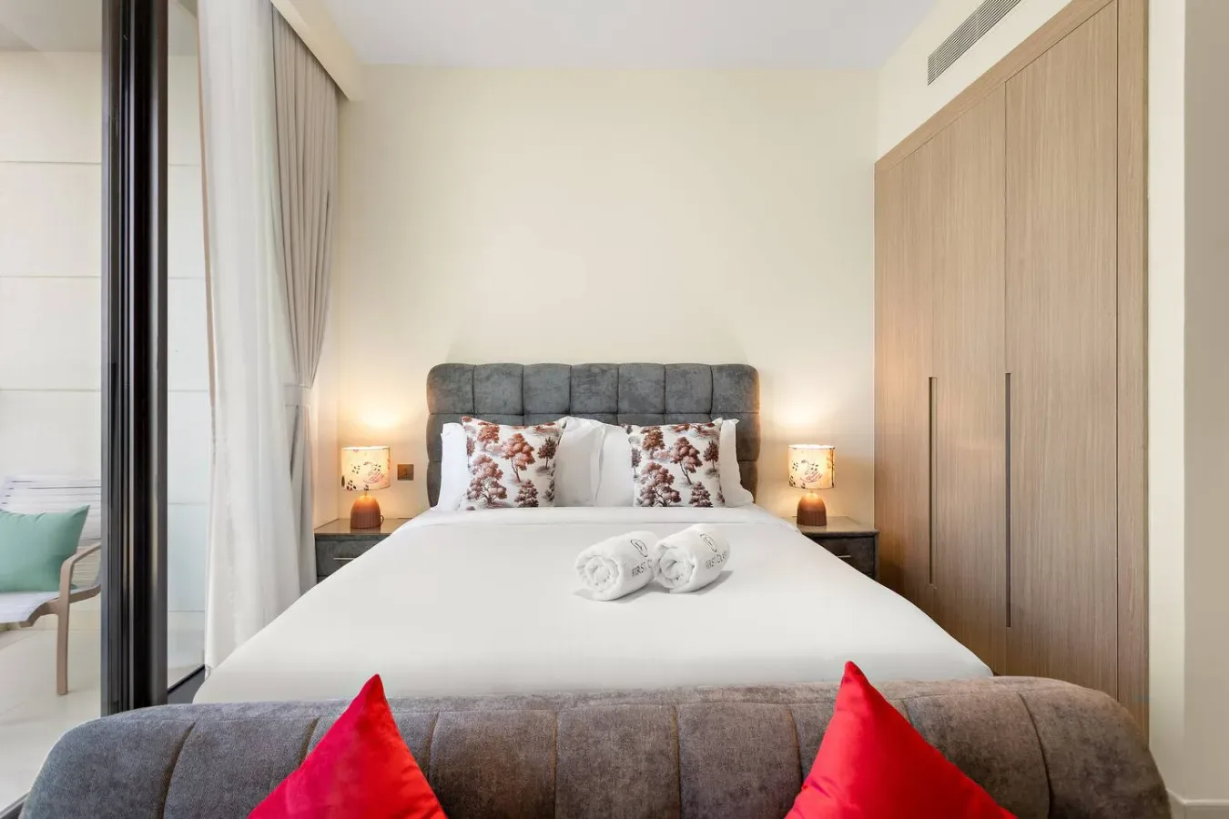 Un dormitorio con una cama tendida, almohadas estampadas y lámparas de noche.