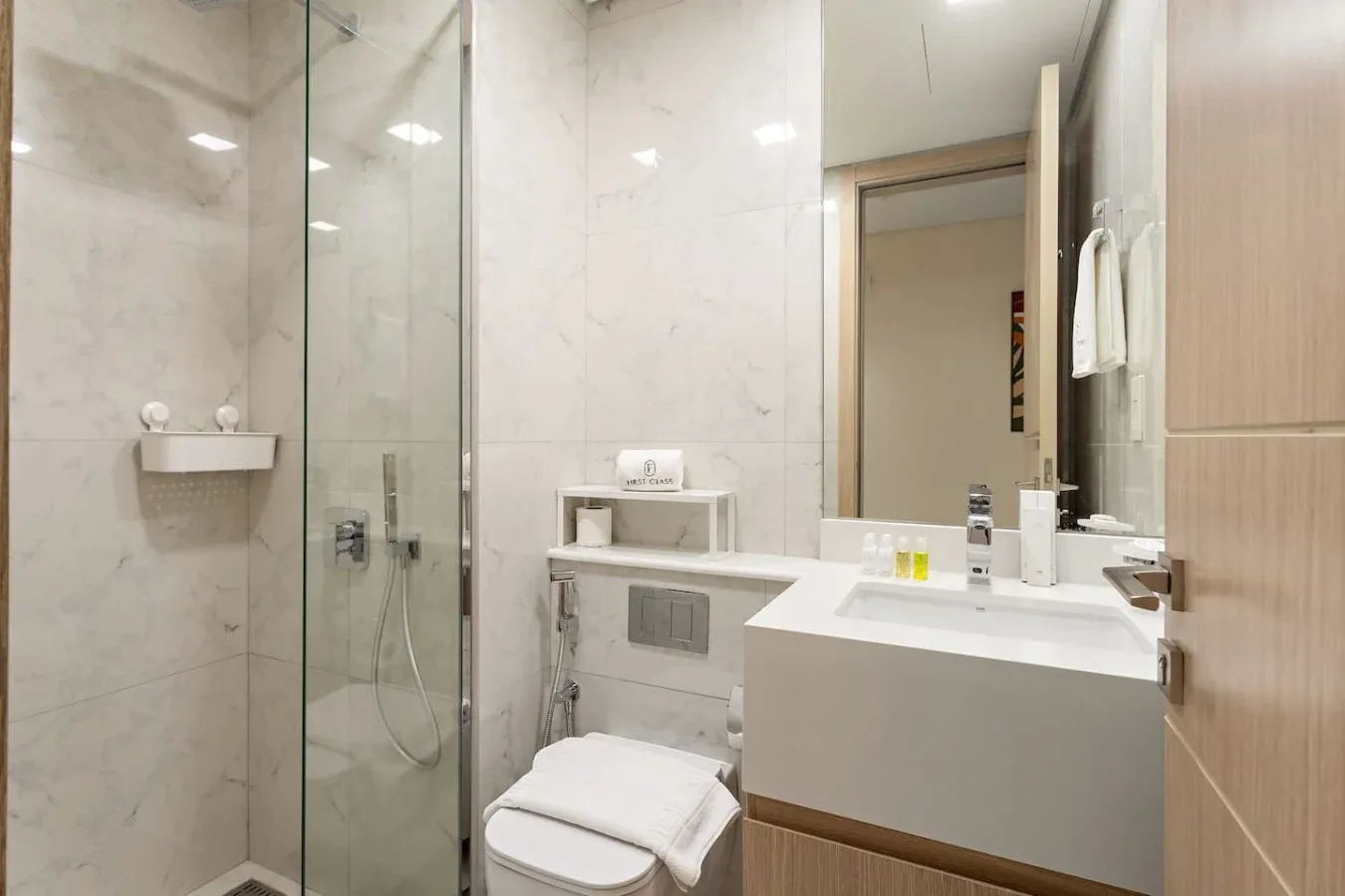 Un baño luminoso con ducha de vidrio y un lavabo con mueble.
