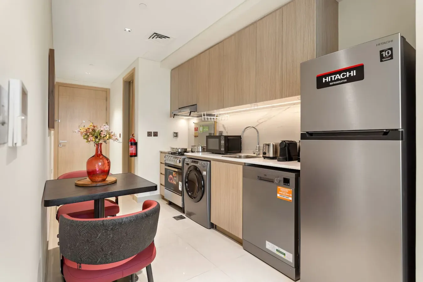 Una cocina compacta con gabinetes de madera, electrodomésticos y una pequeña mesa de comedor.