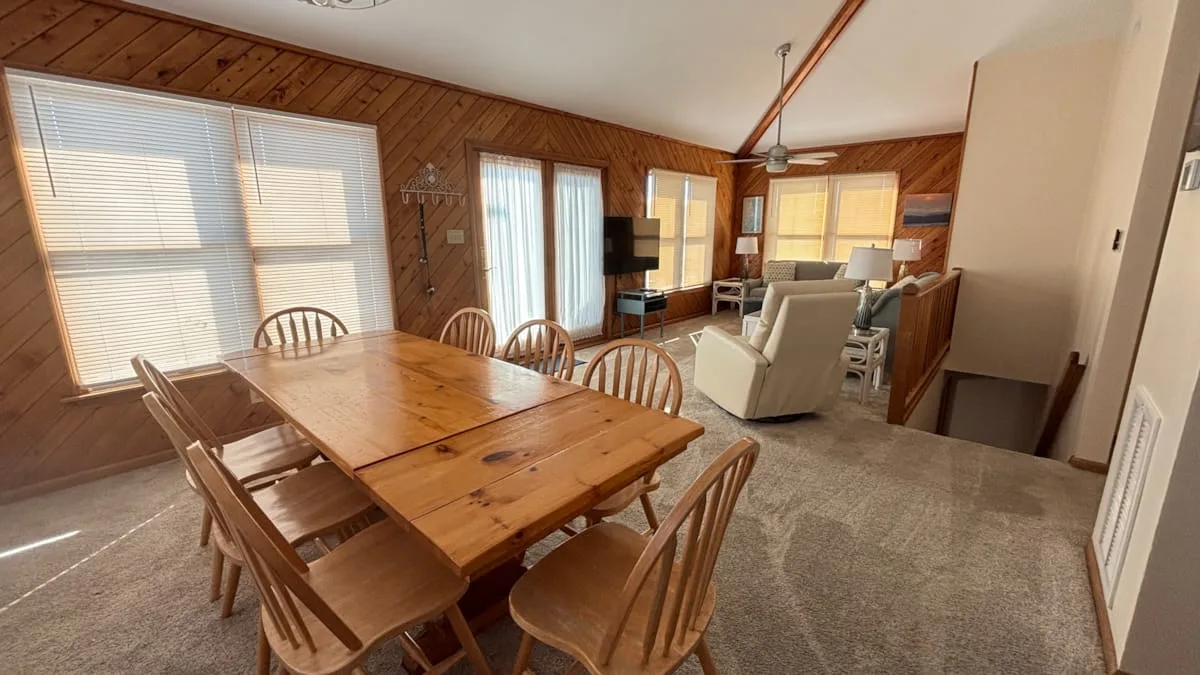 A wood-paneled living and dining room with a wooden dining table and seating.