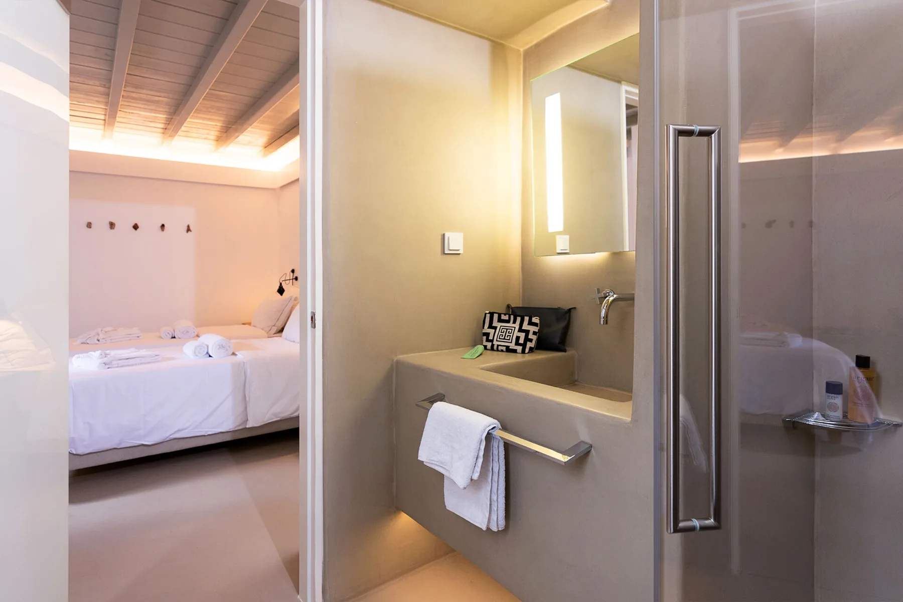 Dormitorio y baño contiguo con una cama y un lavabo iluminado.
