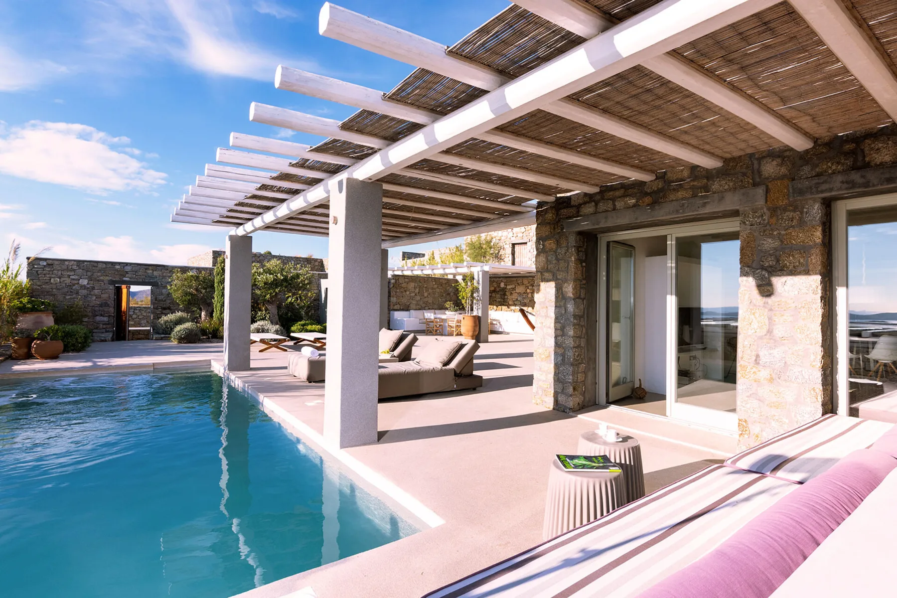 A poolside patio with lounge seating beneath a pergola.