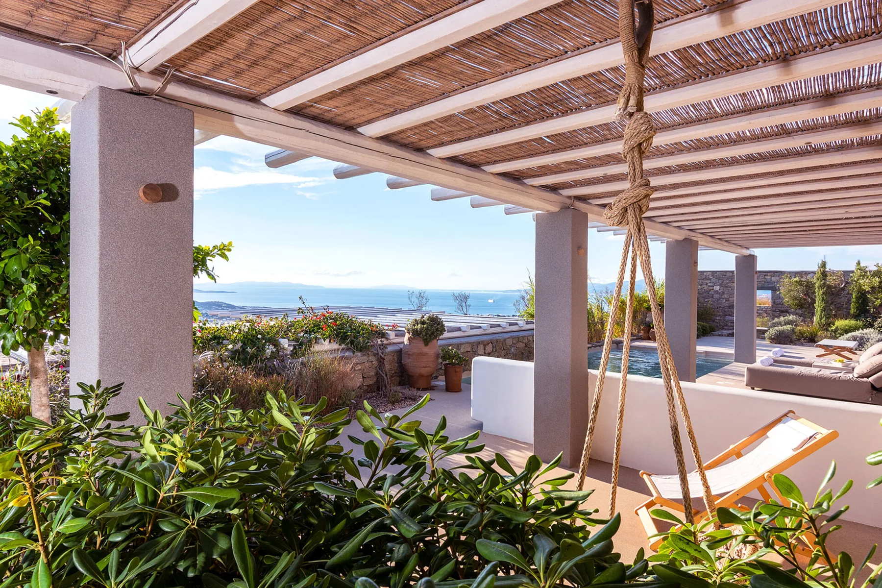 Una terraza sombreada con asientos de descanso ofrece vistas al mar.