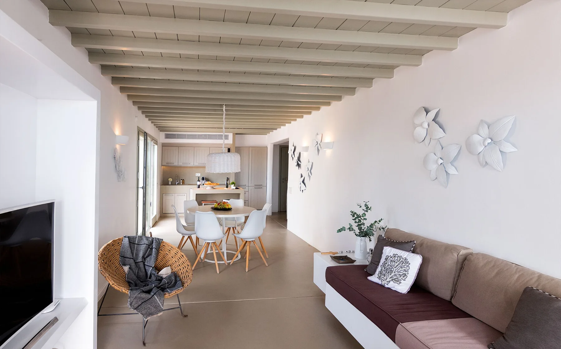 Una luminosa sala-comedor con televisor, asientos y una cocina abierta.