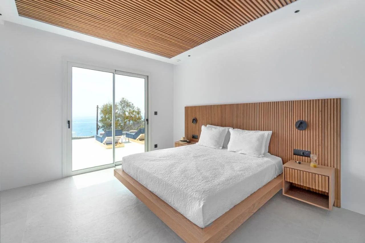 A bright bedroom with a bed beside sliding glass doors.