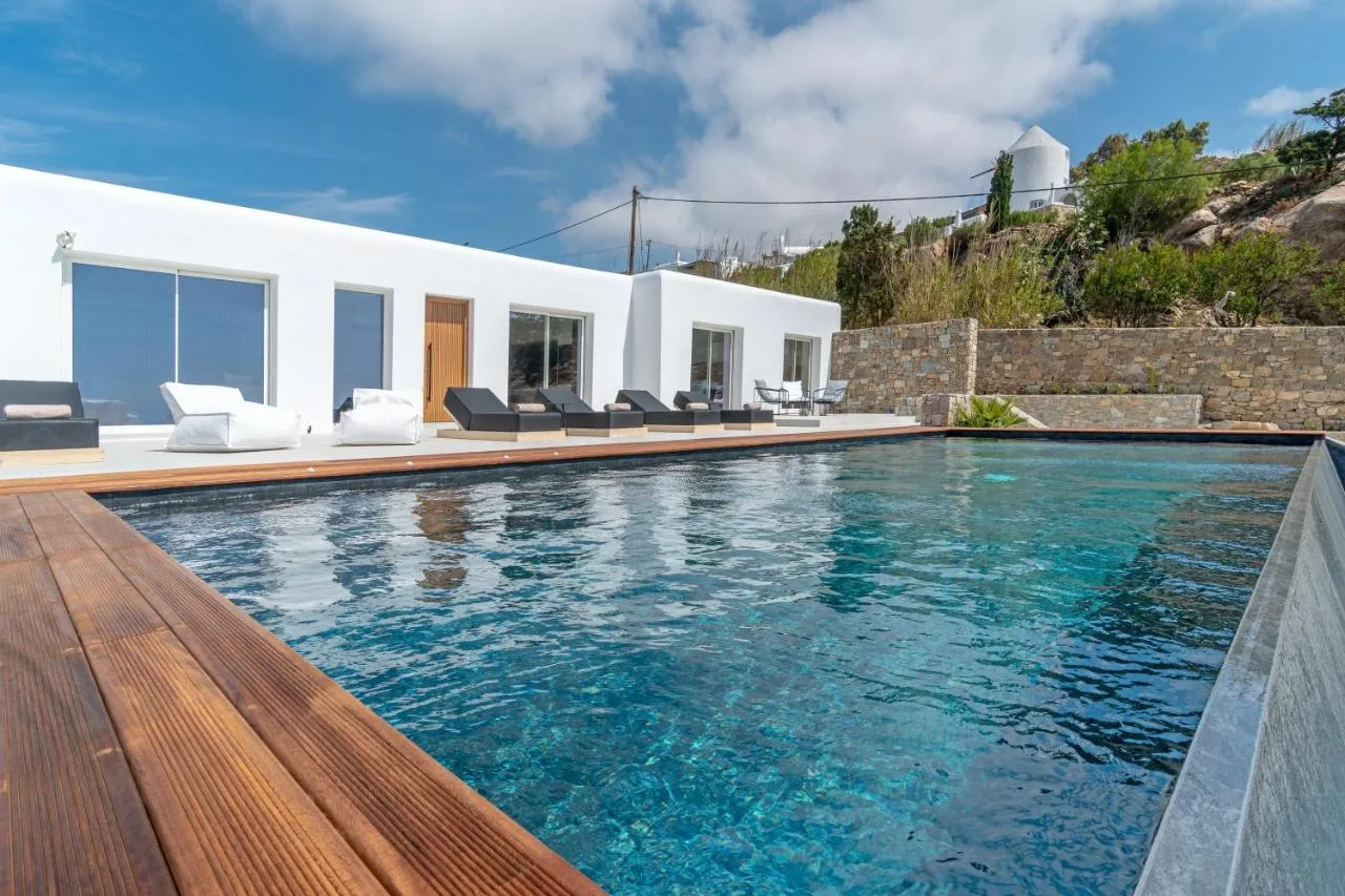 A swimming pool beside a white building, with lounge seating along the deck.